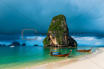 high rock in the sea, rain cloud and Thai boats near the shore