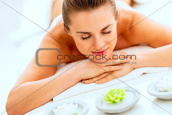 Young woman laying on massage table with candles
