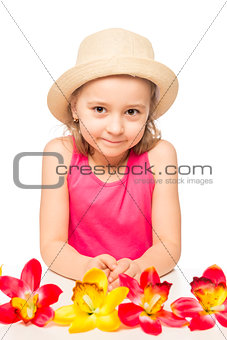  little girl and a bunch of exotic flowers on a table on a white