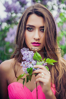 Portrait of young beautiful woman holding a lilac branch