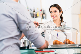 Beautiful waitress serving male customer with a cup of coffee fo