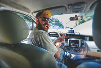 funny smiling bearding man with glass of vine in the car