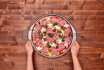 Woman hands with pizza ready to bake in the baking pan