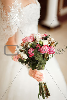 Bride holding a beautiful bouquet of rose and white flowers.