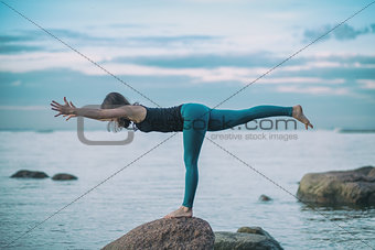 Young attractive woman practicing yoga, standing in Warrior three exercise, Virabhadrasana III pose