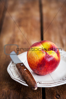 Fresh ripe peach on plate, wooden background