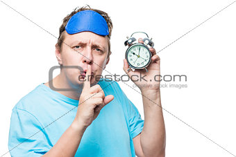 Man with an alarm clock showing a gesture quietly in a mask for 