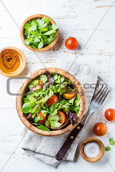 Vegetarian salad with lettuce and tomatoes in olive wooden bowl