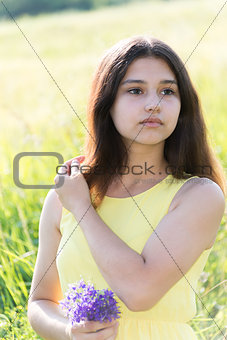 Girl 14 years with bouquet of wildflowers in summer field