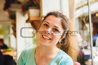 Portrait of a cute blonde smiling woman sitting in a cafe
