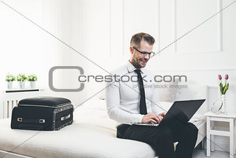 Businessman on bed working with a laptop from his hotel room