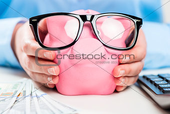 Pig stuffed with money in the hands of an economical woman close