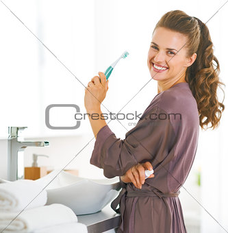 Portrait of smiling woman with toothbrush in bathroom