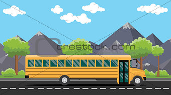 school bus yellow on road with tree and mountain as background