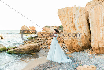 Romantic beautiful bride in luxury dress posing on the beach.