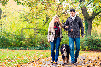 Woman and man with dog having autumn walk