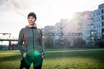 Determined young woman daydreaming while holding a skipping rope