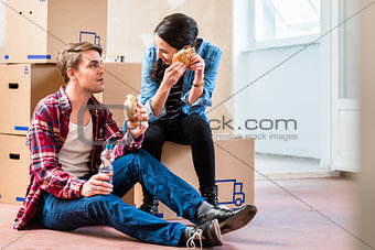 Young couple looking tired while eating a sandwich during break