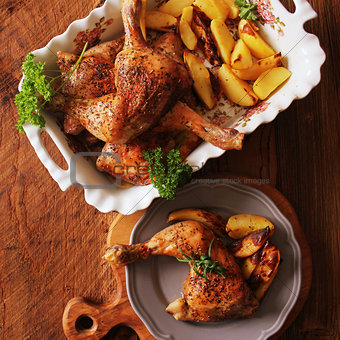 Grilled chicken quarter with potato for garnish. Top view. Wooden background
