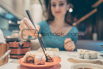 Woman eating sushi food in Japanese restaurant