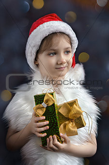 Little girl in hat of Santa Claus with gifts in his hands, colorful bokeh