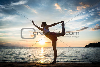 Fit woman practicing on the beach the standing bow pulling pose
