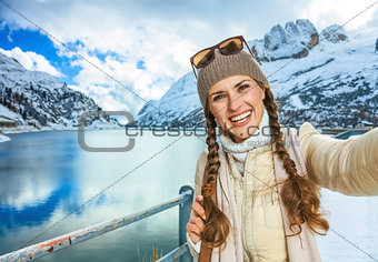 smiling young woman in winter Alto Adige, Italy taking selfie