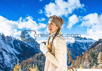 tourist woman against mountain scenery with thermos travel mug