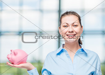 horizontal portrait of a successful woman with a pink piggy bank