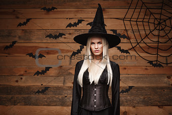 Halloween witch concept - Happy Halloween Sexy Witch holding posing over old wooden studio background.