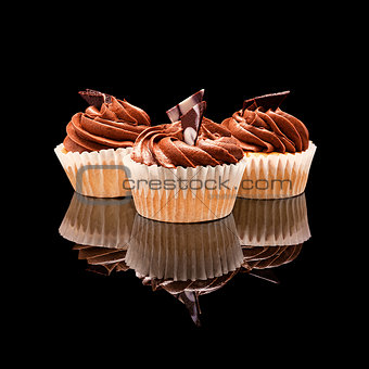 Three muffin cupcake with brown cream and pieces of chocolate