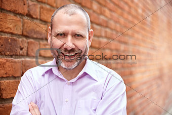 Smiling man against a brick wall