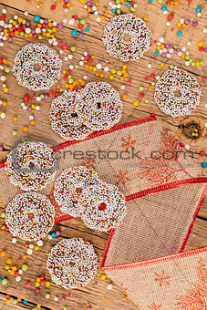 Colored chocolate rings with Christmas decoration on wood