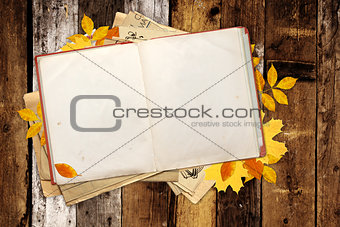 Old book and autumn leaves on wooden boards
