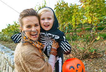 smiling modern mother and daughter on Halloween outdoors