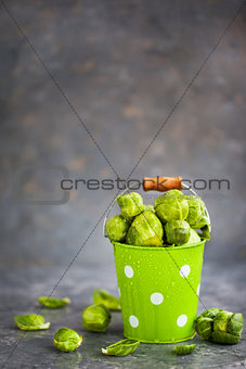 Organic fresh raw brussels sprouts in a metal bucket on gray bac