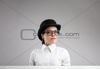 serious woman in bowler, glasses and white shirt