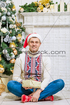 portrait of a man with a gift near a Christmas fir
