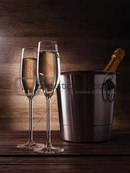 Image of two wine glasses with champagne, steel bucket and bottle