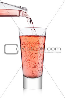 Pouring pink soda lemonade from bottle to glass