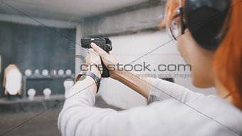 Woman shooting with a gun in shooting gallery