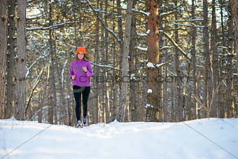 Young Woman Running in Beautiful Winter Forest at Sunny Frosty Day. Active Lifestyle Concept.