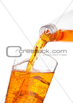 Pouring orange energy drink from bottle to glass