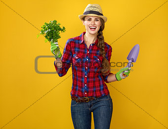 smiling woman grower with fresh parsley and gardening tool