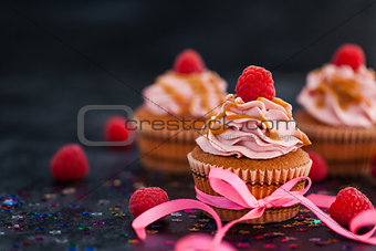 Raspberry and caramel cupcakes on dark background