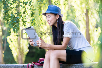 Asian woman using a tablet PC outdoors