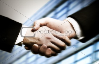 business hand shake and a office in background