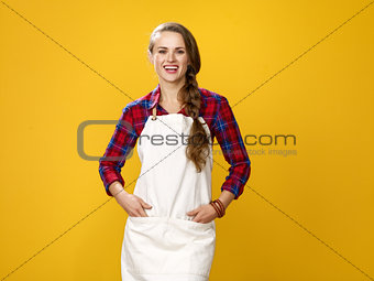 happy young woman farmer wearing apron isolated on yellow
