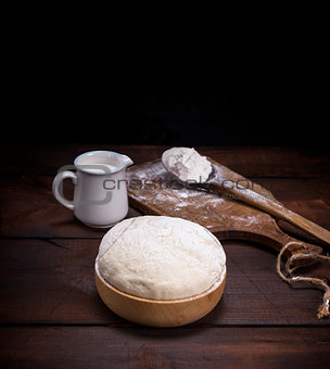 wheat yeast dough in a wooden bowl on a table