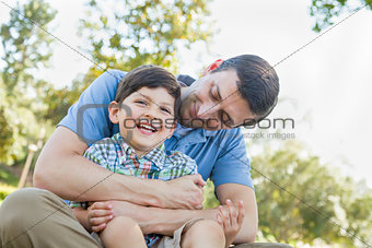 Loving Young Father Tickling Son in the Park.
